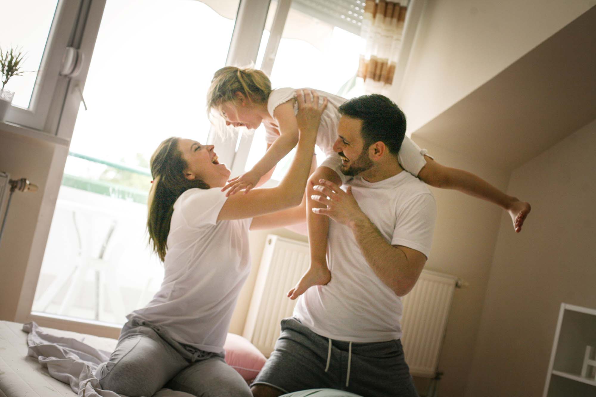 Happy family child baby girl in the arms of his father at home window